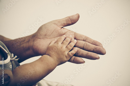 Old female hand holding young baby hand in vintage tone photo