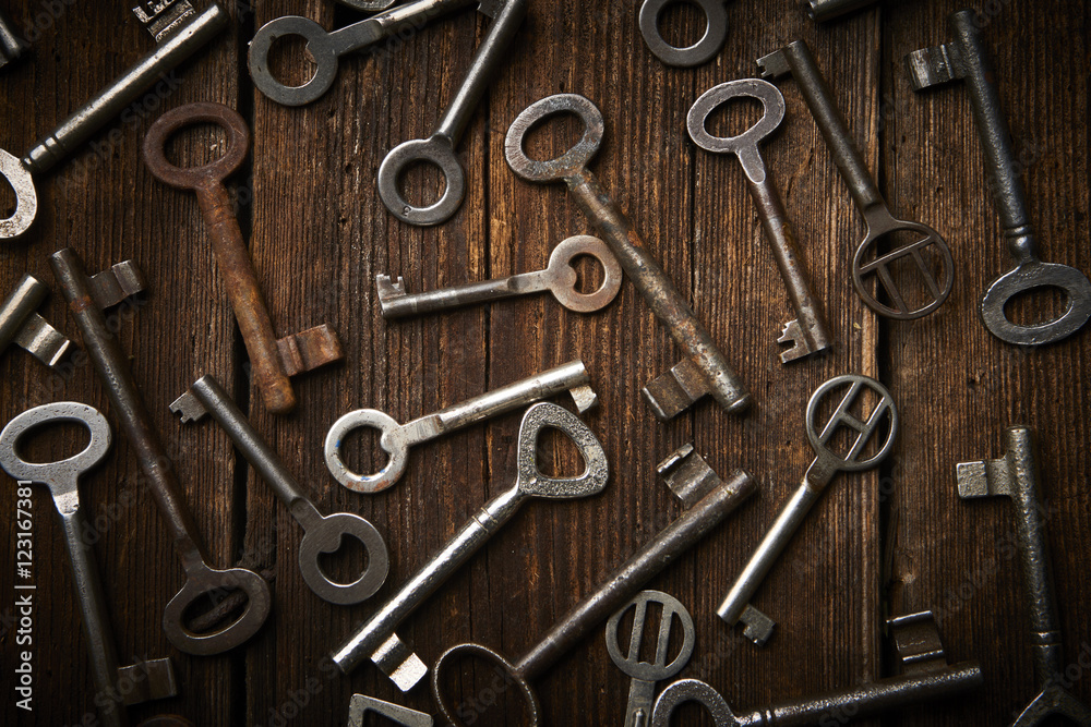 Fototapeta premium many different keys on brown wooden background.