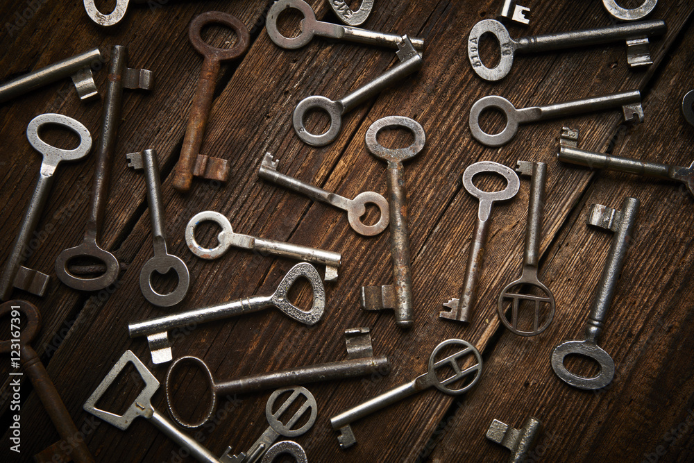 many different keys on brown wooden background.
many different keys on brown wooden background.
