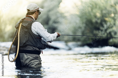 Canvas Print Fly fisherman using flyfishing rod.