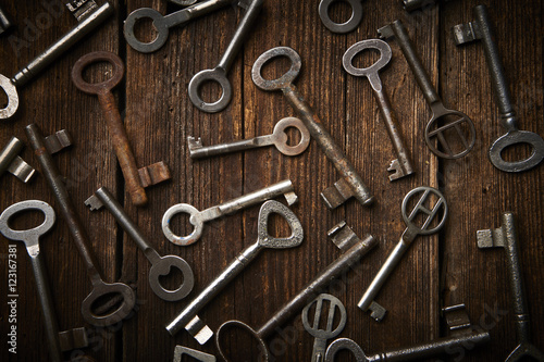 many different keys on brown wooden background. 