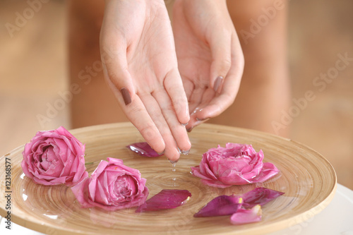 Female hands in spa wooden bowl with flowers, closeup