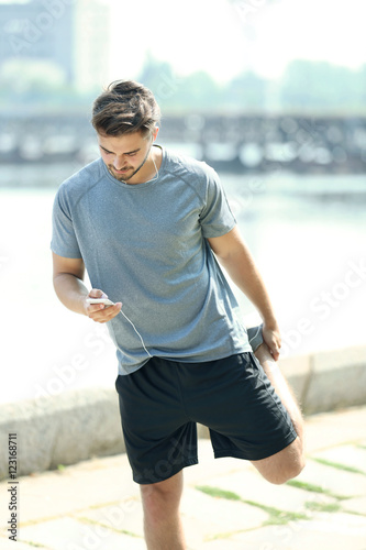 Sporty man doing workout and listening music outdoors