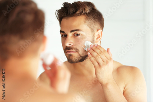 Young man shaving and looki...