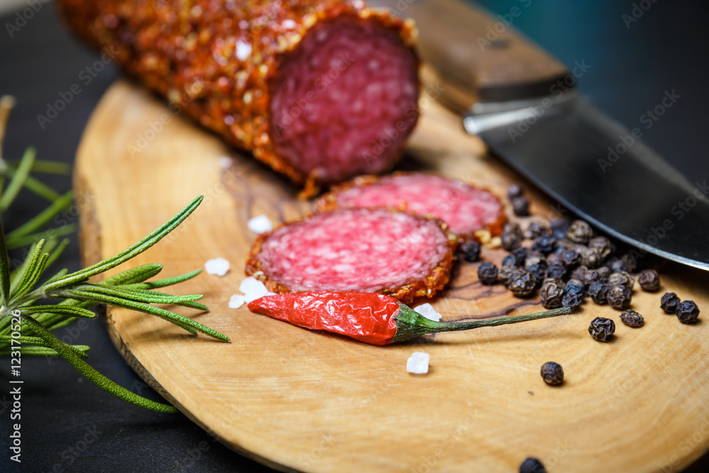 dried salami crusted in ground red pepper on dark background dried salami crusted in ground red pepper on dark background