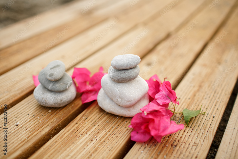 Zen stones spa at sandy beach with tropical pink flowers Zen stones spa at sandy beach with tropical pink flowers