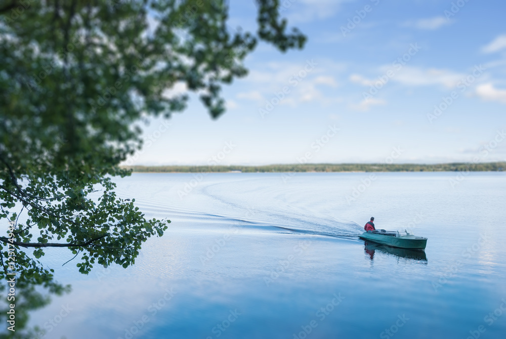 Motor boat swam to the shore of the lake. Tilt shift blur effect.