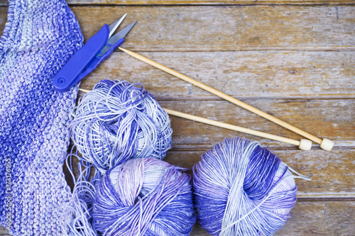 Knitting purple yarn on wooden background/natural wool knitting