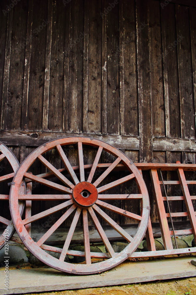 Wooden wheels leaning onto wooden house Wooden wheels leaning onto wooden house