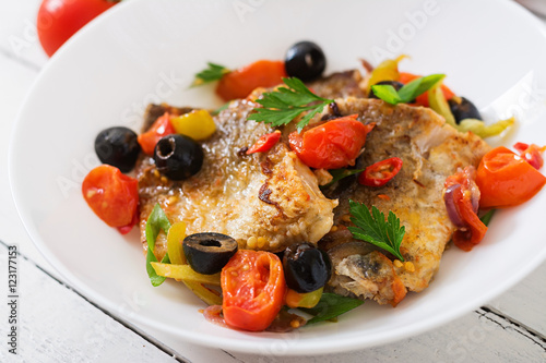 Fried hake fillet with tomato and olives in the Mediterranean style