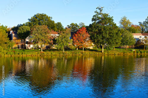A waterfront townhouses among colorful trees at dawn in Washington DC. Picturesque autumn foliage with reflections in the lake in North Virginia.
