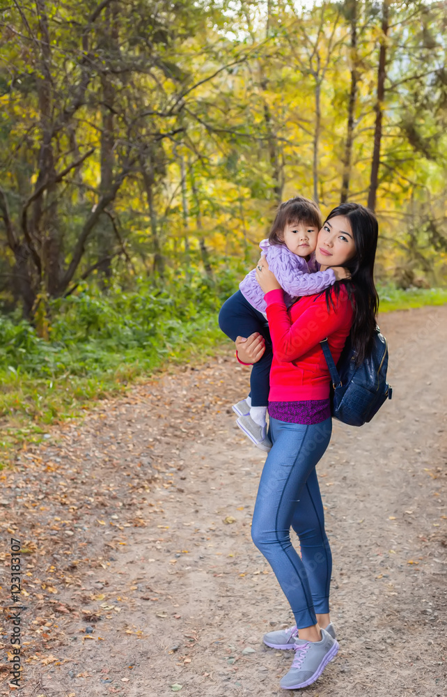 Asian appearance mother walking with her child in warm sunny autumn day Asian appearance mother walking with her child in warm sunny autumn day