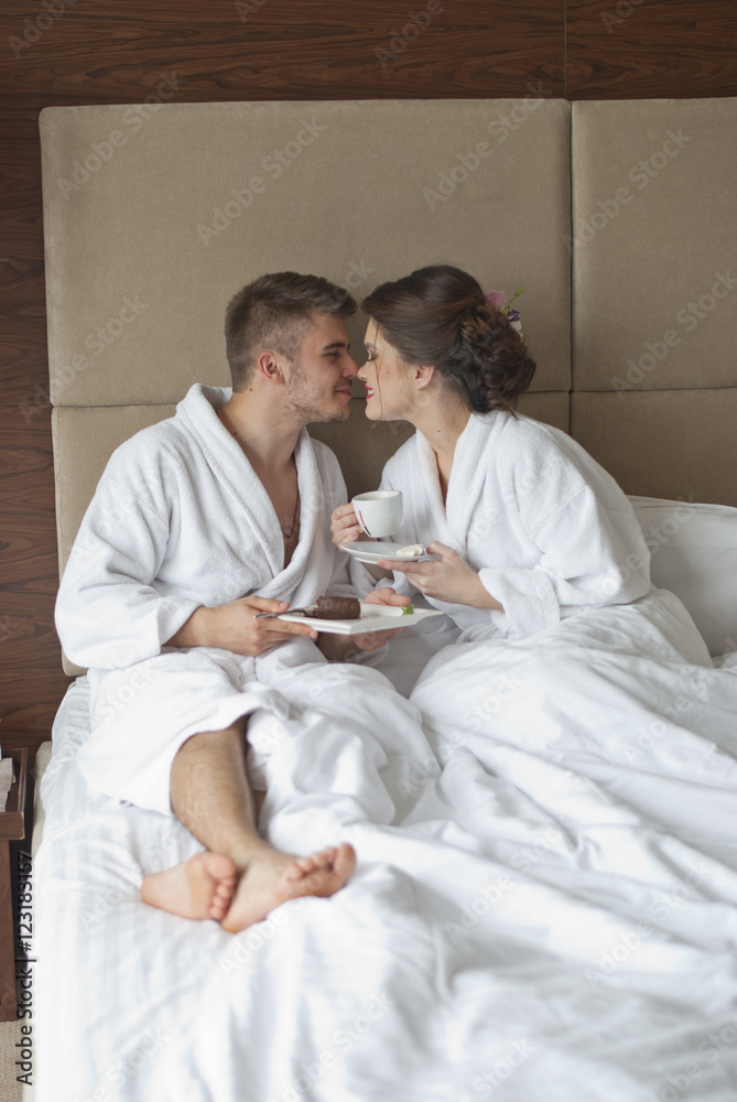 Beautiful young couple having breakfast in bed. 