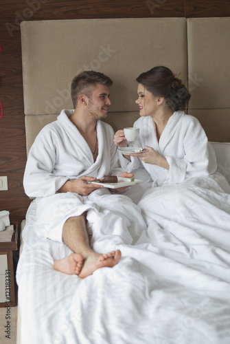 Beautiful young couple having breakfast in bed. 