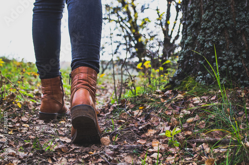 Female legs shod in Hiking boots on the forest background
