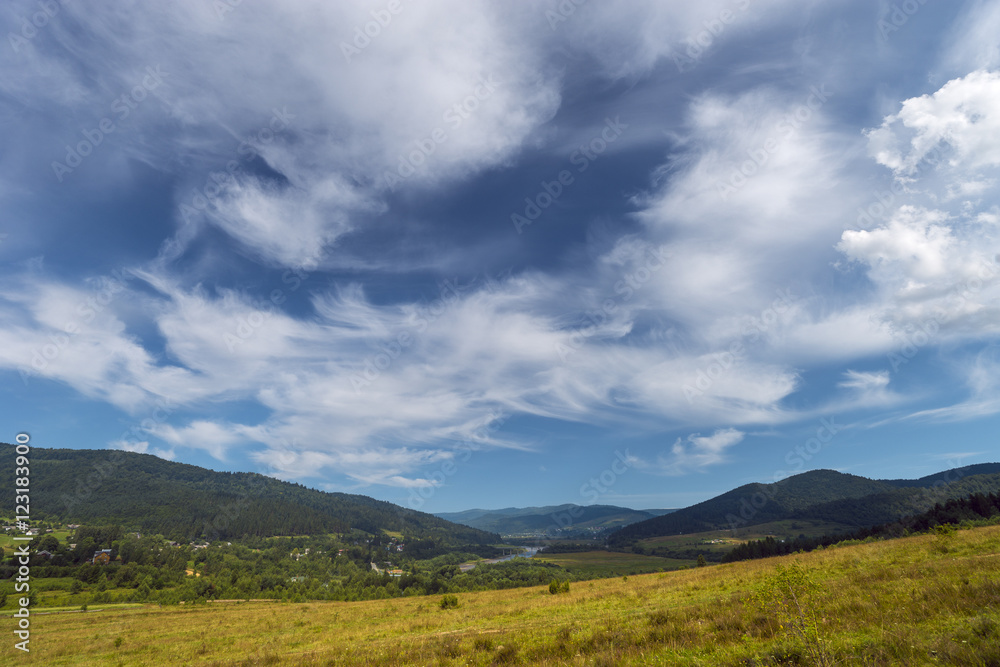 Summer day landscape with clouds, mountains and houses Summer day landscape with clouds, mountains and houses