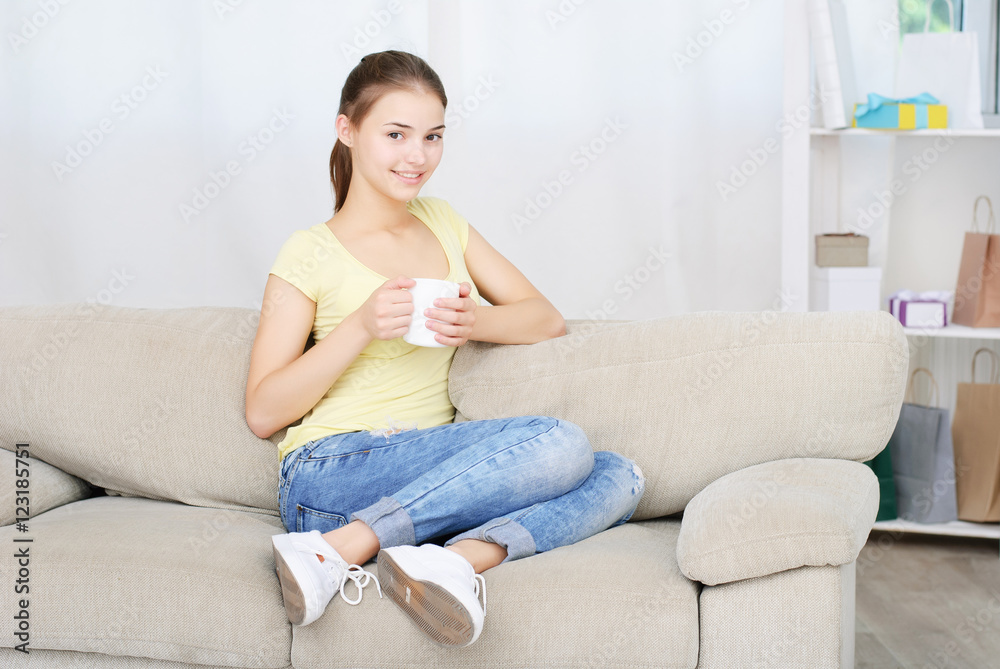 young woman sitting on couch and drinking coffee
