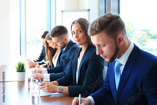 Smiling businesswoman looking at camera at seminar with her colleagues near by