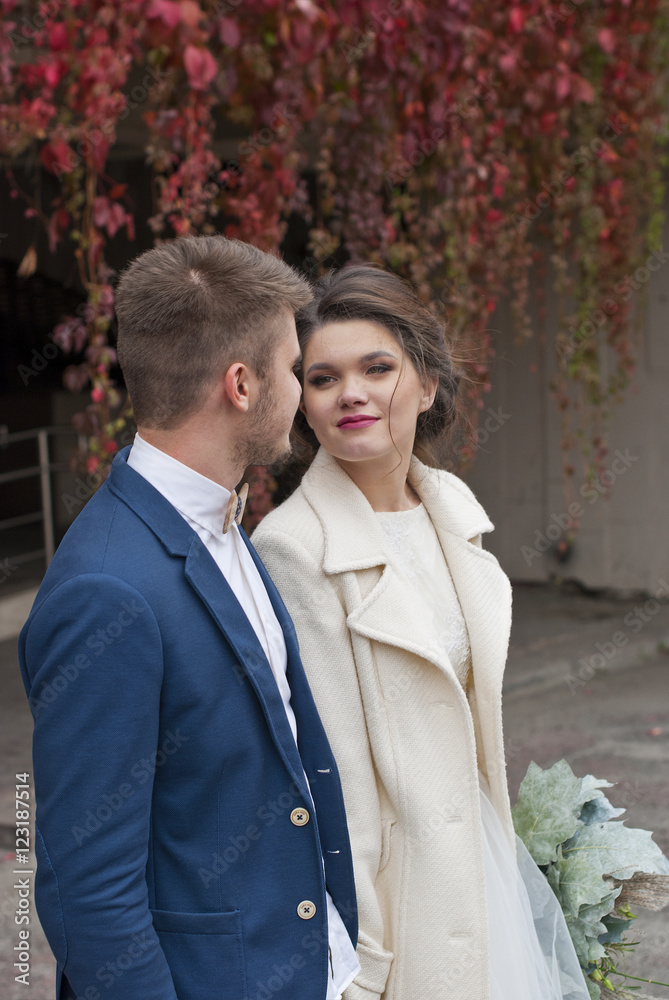 Just married loving couple in wedding dress and suit outdoor in city setting against wall. Happy bride and groom laughing and kissing. Romantic Married young family. Just married loving couple in wedding dress and suit outdoor in city setting against wall. Happy bride and groom laughing and kissing. Romantic Married young family.