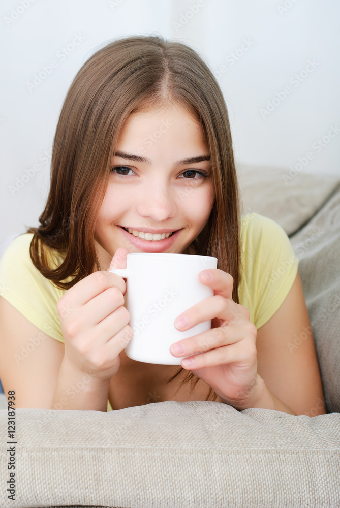 young woman sitting on couch and drinking coffee