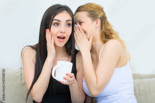 Two happy friends talking and drinking coffee or tea
