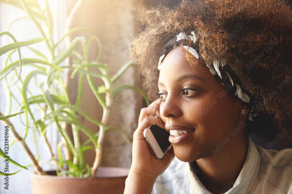 Close up portrait of attractive stylish dark-skinned girl with Afro  hairstyle wearing bandana talking on mobile phone to her boyfriend looking  aside, isolated against home interior background Stock Photo | Adobe Stock