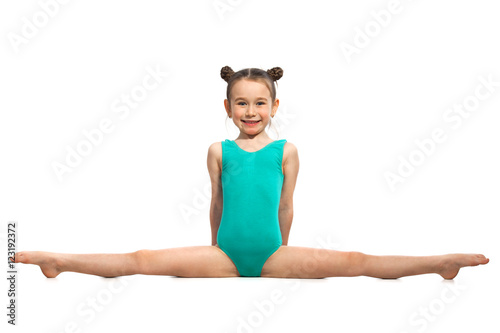Little girl gymnast sitting in the splits. Isolated on white