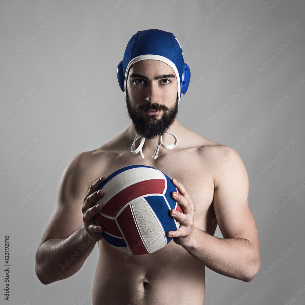 Confident proud portrait of professional water polo player holding ball looking at camera.