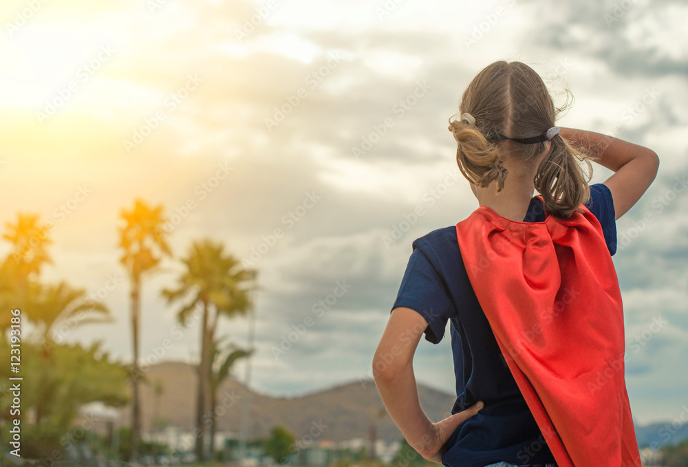 Superhero kid looking on the sunset.