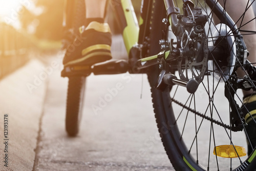 Cyclist legs on bicycle on street in sunset background