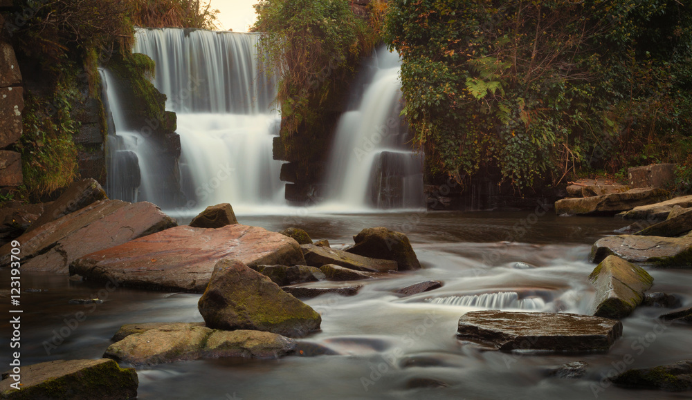 Fototapeta premium Autumn colours start to appear around the waterfalls at Penllergare woods, Swansea, UK