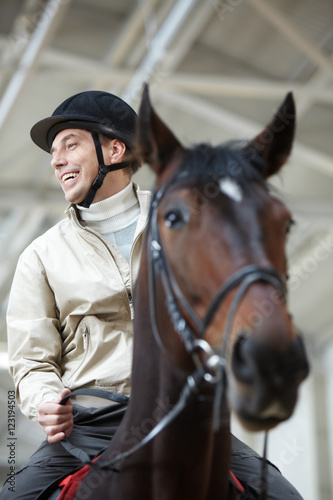 A cheerful man riding a horse © pressmaster