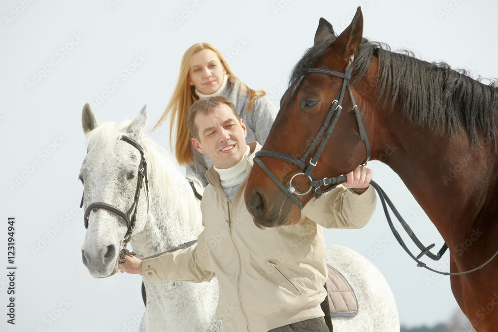 Obraz premium A young man leading two horses, one of them is ridden by a woman