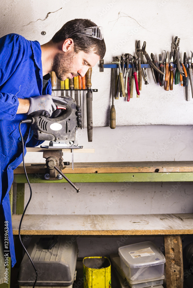 Caucasian handyman using jigsaw with safety gloves and glasses Caucasian handyman using jigsaw with safety gloves and glasses