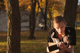 Young man reading book in autumn Park,