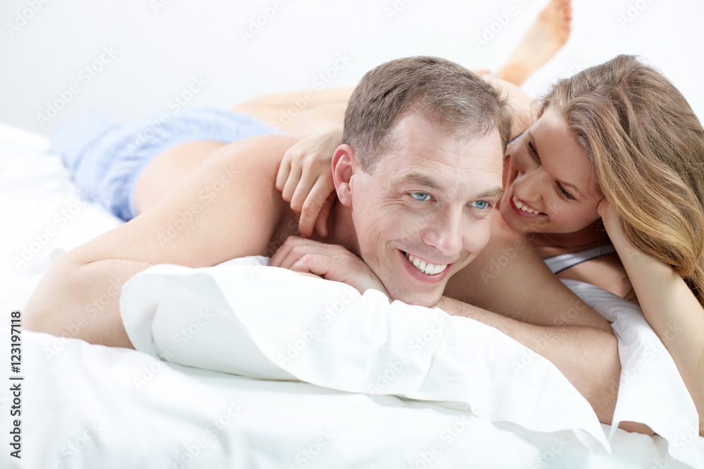 Two happy people lying together in bed and smiling Two happy people lying together in bed and smiling