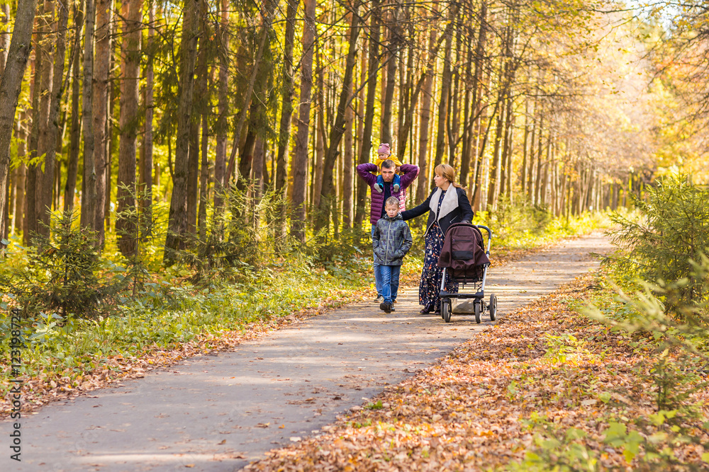 Young Family Outdoors Walking Through Autumn Park Young Family Outdoors Walking Through Autumn Park