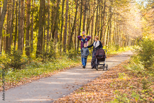 Young Family Outdoors Walking Through Autumn Park