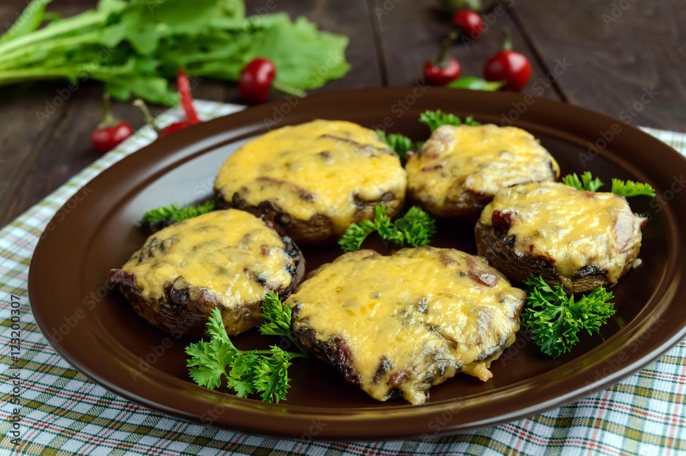 Stuffed mushrooms with salami and mozzarella cheese in a clay bowl on a wooden background.