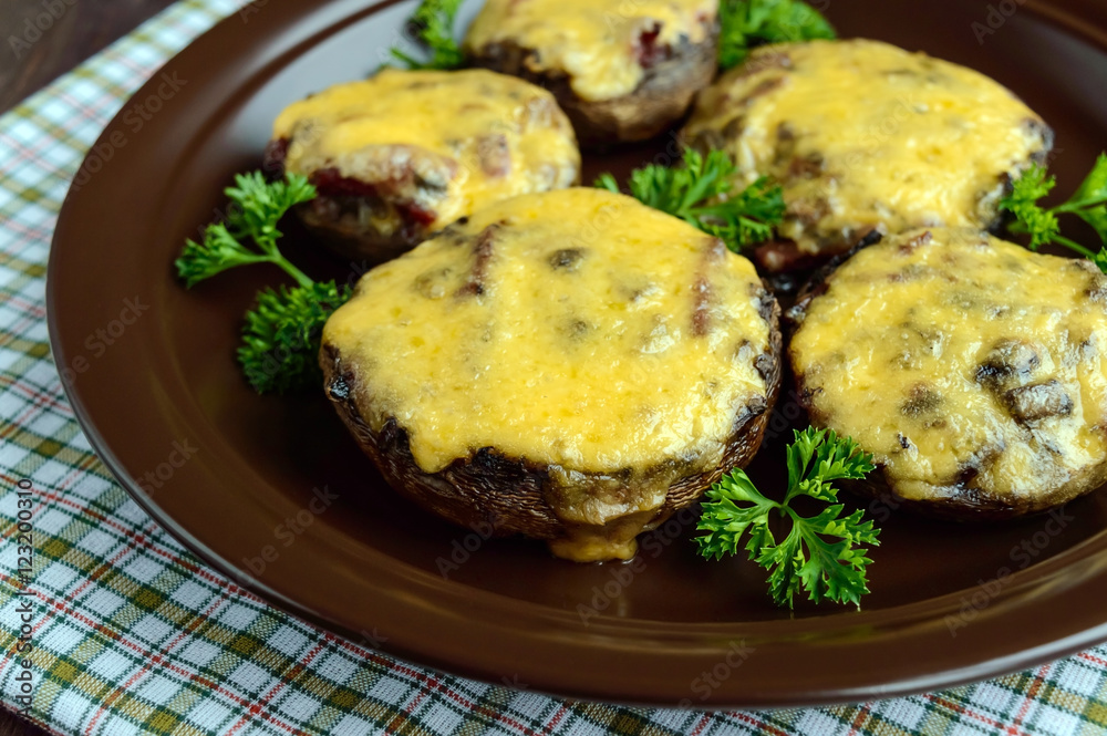 Stuffed mushrooms with salami and mozzarella cheese in a clay bowl on a wooden background. Close up
