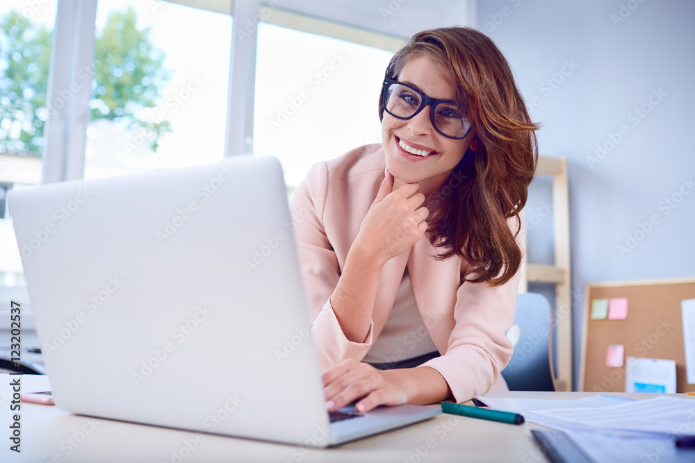 Portrait of happy woman working on laptop from home office