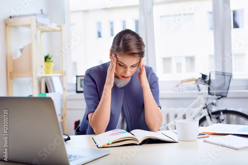 Stressed businesswoman sitting by her desk at office