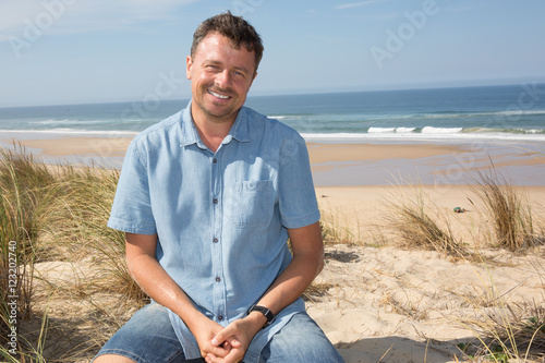 Smiling man with a blue shirt on the ocean under blue sky