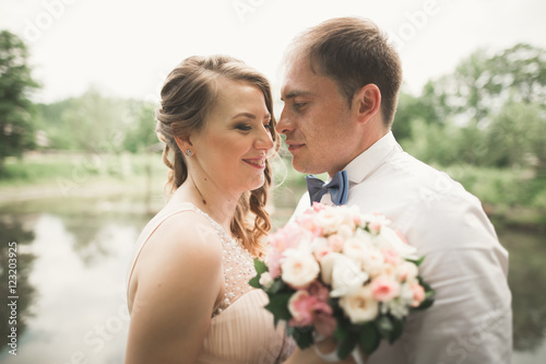 Bride and groom holding beautiful wedding bouquet. Lake, forest