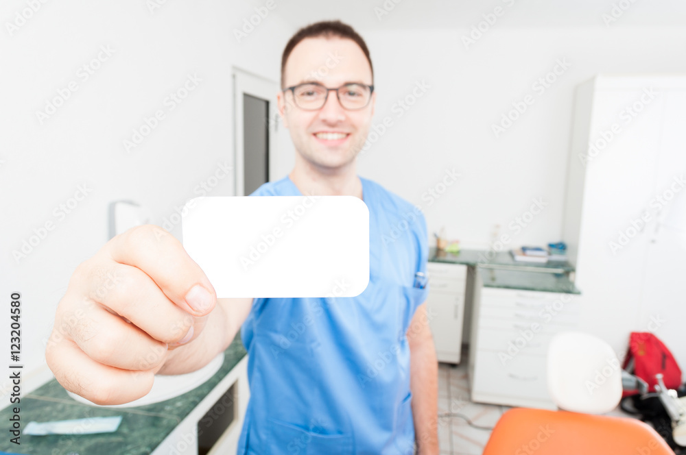 Happy handsome dentist showing business card Happy handsome dentist showing business card