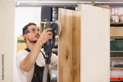 Fotografie man polishes boards. carpenter with sander