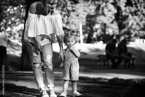 Black and white photo of stylish young mother walking with her l