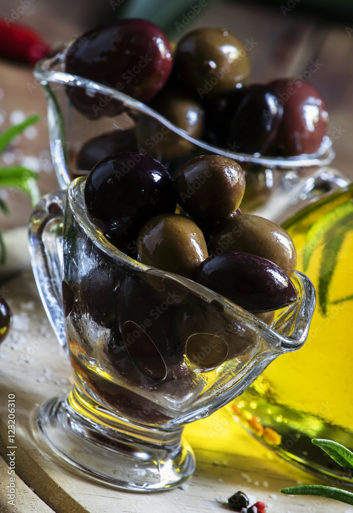 Greek olives in a glass bowl and oils, dark wood background, sel Greek olives in a glass bowl and oils, dark wood background, sel