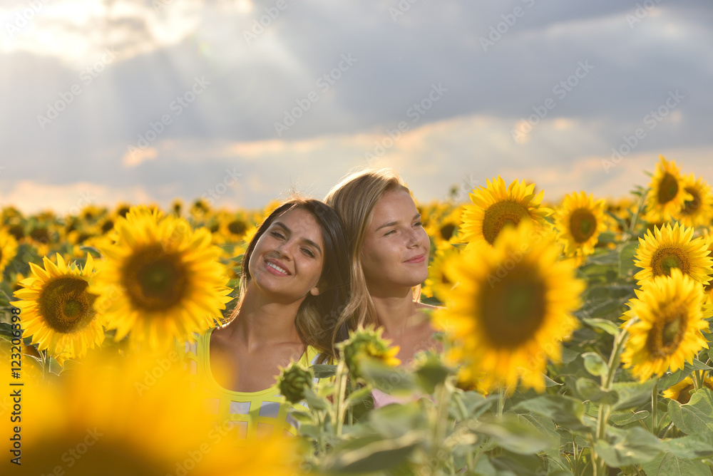 Two beautiful girls feeling free in a lovely sunflower field at sunset Two beautiful girls feeling free in a lovely sunflower field at sunset