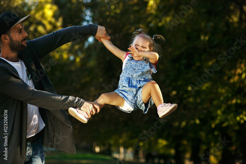 Cheerful girl has fun while dad whirls her in the air